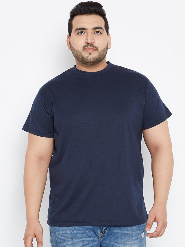Plus size man wearing a plain navy blue t-shirt and blue jeans against a white background