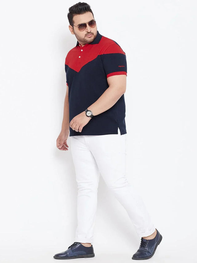 Plus size man wearing red and navy colorblock polo t-shirt with white pants and blue shoes