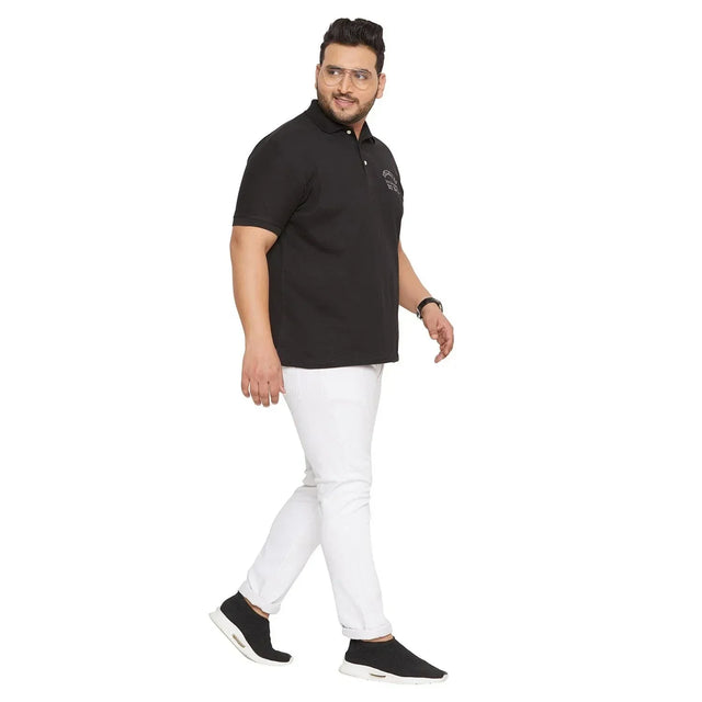 Plus size man wearing black polo t-shirt and white jeans, walking, isolated on white background