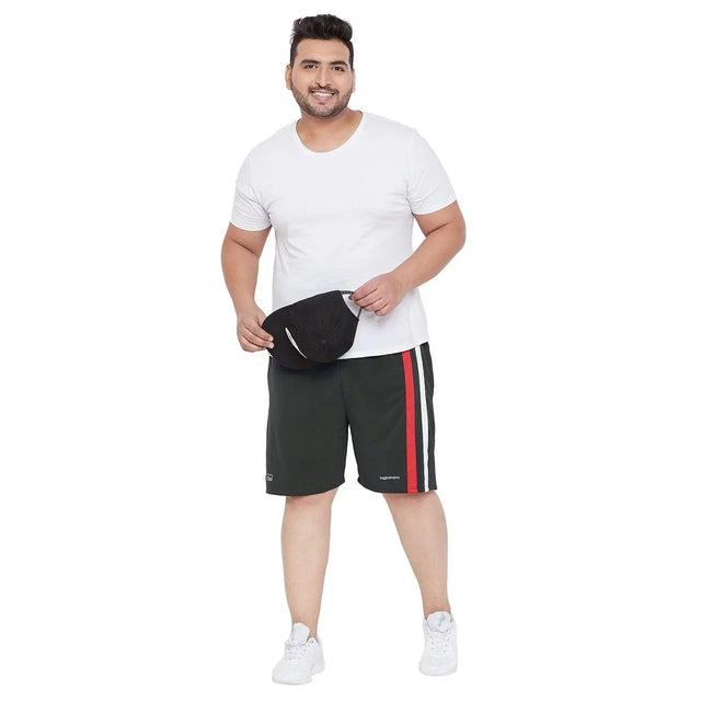 Plus size man in white t-shirt and black shorts with red stripe, holding a black cap
