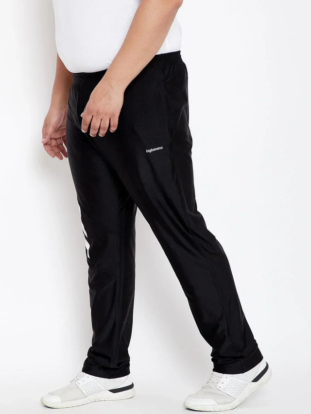 Men's plus size black joggers with elastic waist, side logo, and white sneakers