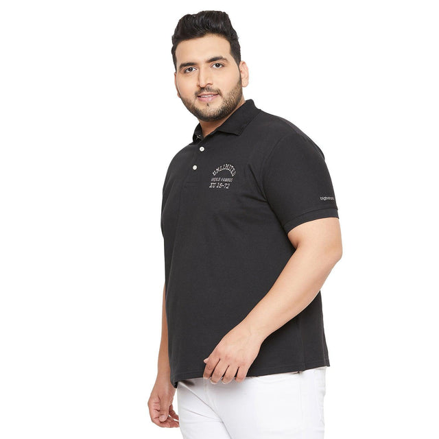 Plus size man wearing black polo t-shirt with embroidered text, paired with white pants