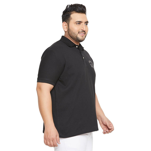 Plus size man wearing a black polo t-shirt with short sleeves, white pants, side pose