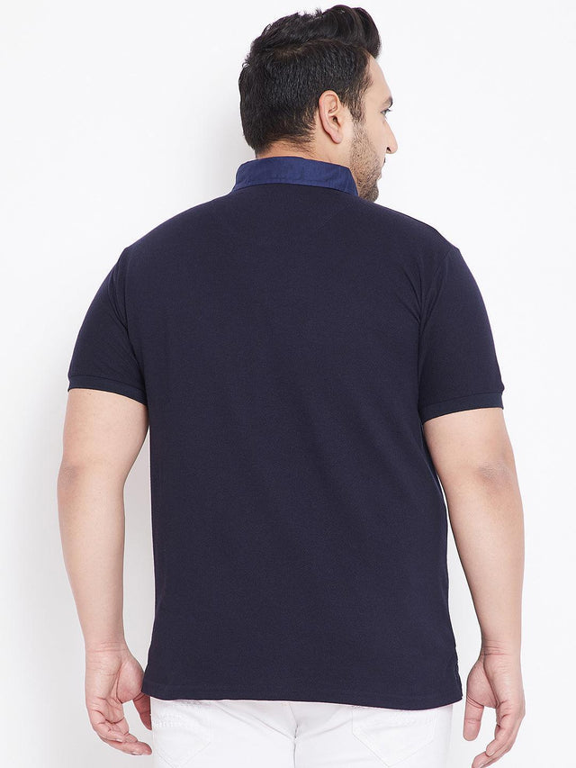 Back view of a man wearing a navy blue plus size polo t-shirt and white pants