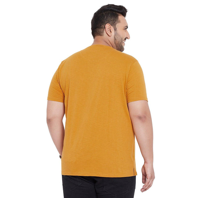 Back view of a man wearing a mustard yellow plus size t-shirt and black jeans