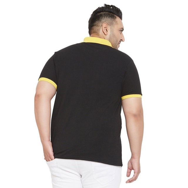 Plus size man in black polo shirt with yellow collar and trim, back view, white jeans