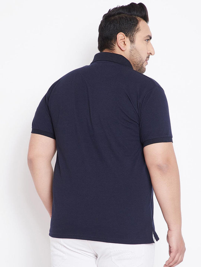 Plus size man wearing dark navy polo shirt and white pants, back view