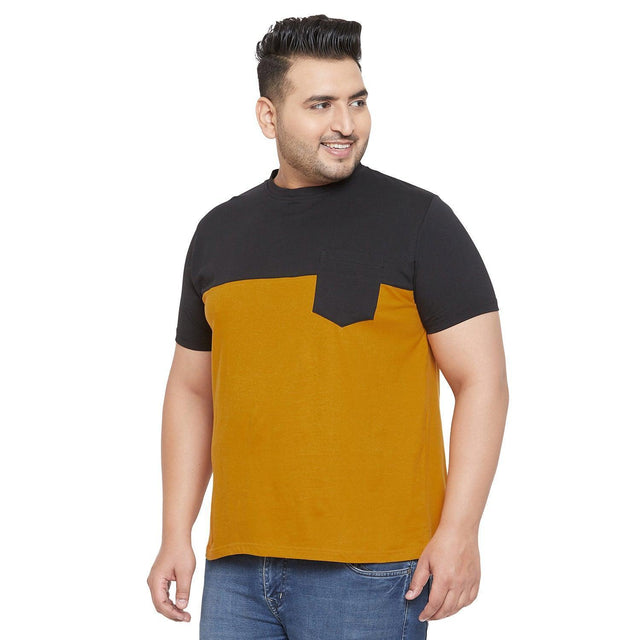 Plus size man in a black and mustard colorblock t-shirt with front pocket, blue jeans
