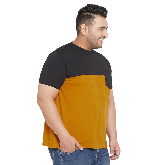 Plus size man wearing a short sleeve black and mustard colorblock t-shirt with jeans
