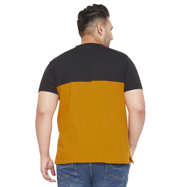 Back view of a plus size man wearing a colorblock black and mustard t-shirt with blue jeans