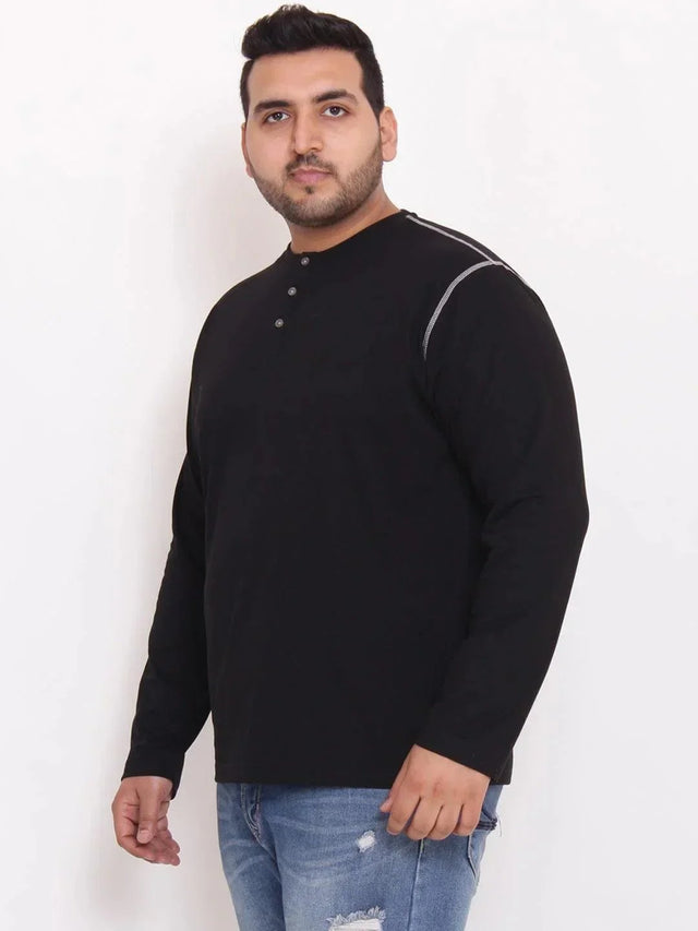 Plus size man wearing a black long sleeve henley t-shirt and blue distressed jeans