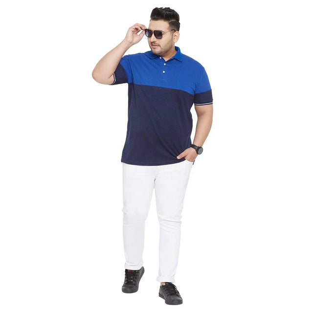 Plus size man wearing a blue colorblock polo shirt, white pants, and black shoes