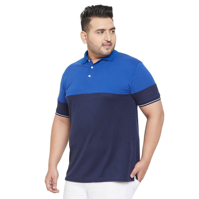 Plus size man wearing a blue and navy colorblock polo shirt with white pants