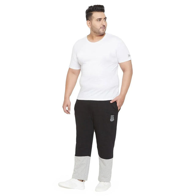 Plus size man in a white t-shirt and black joggers with grey ankle panels, standing