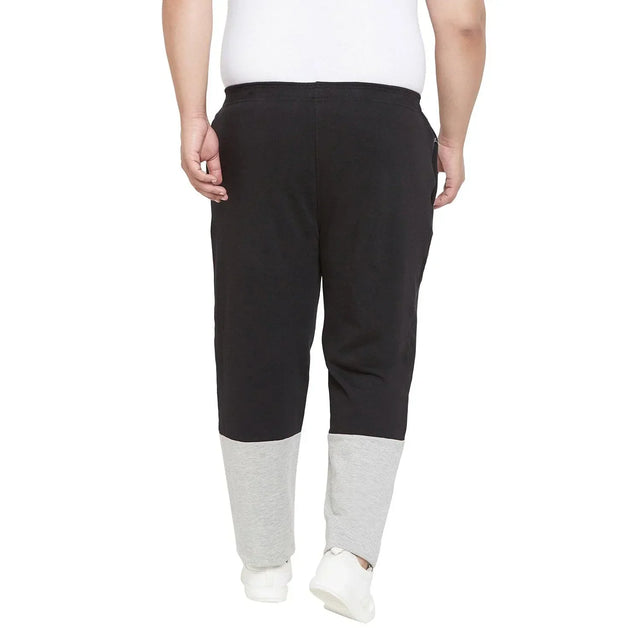 Back view of a man wearing plus size black joggers with grey cuffs and white sneakers